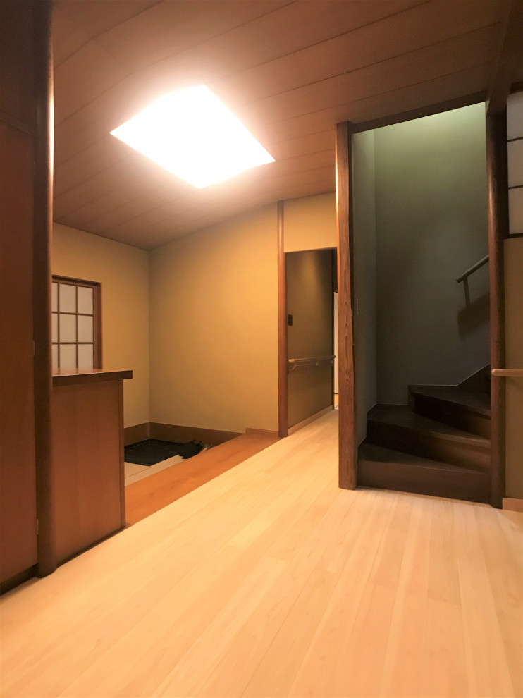 Cette image montre une entrée de taille moyenne avec un couloir, un mur beige, parquet clair, une porte coulissante, une porte marron et un sol beige.