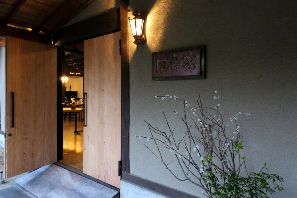 Asiatischer Eingang mit weißer Wandfarbe, braunem Holzboden, heller Holzhaustür und braunem Boden in Sonstige