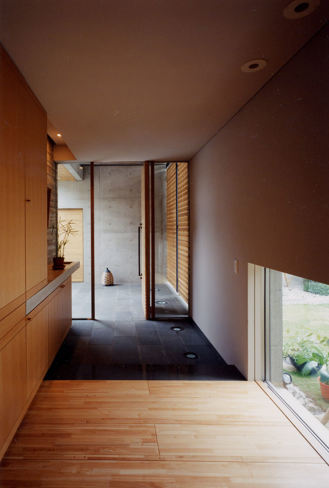 Idéer för en asiatisk hall, med en pivotdörr, mellanmörk trädörr, vita väggar och grått golv