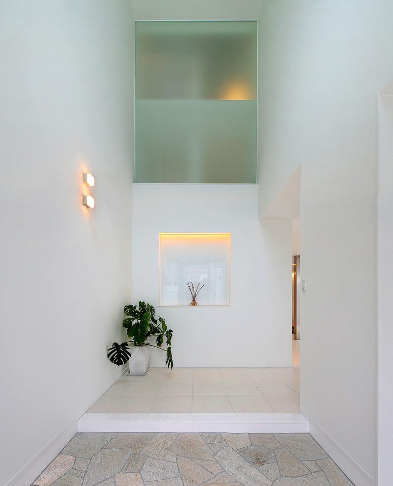 Bild på en funkis entré, med vita väggar och grått golv