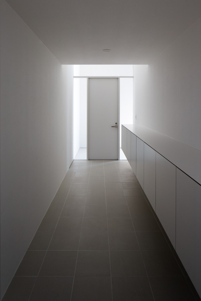 Cette photo montre une entrée moderne avec un mur blanc, un sol en carrelage de porcelaine, une porte simple, une porte blanche, un sol gris, un plafond en papier peint et du papier peint.
