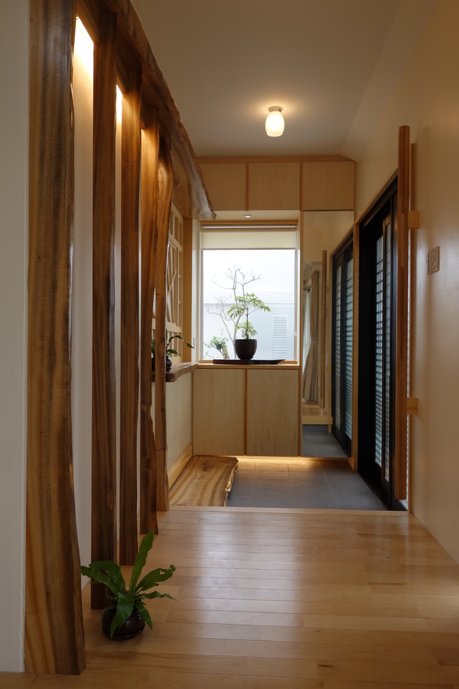 Asiatischer Eingang mit beiger Wandfarbe, braunem Holzboden und braunem Boden in Sonstige