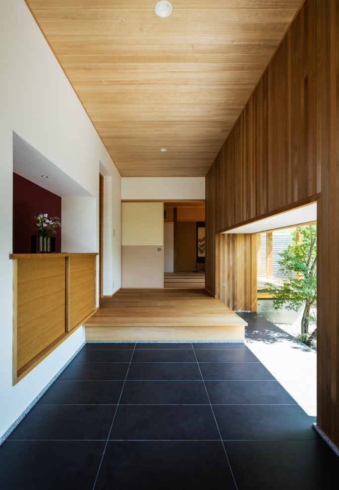 Aménagement d'une entrée asiatique en bois avec un couloir, un mur marron, un sol en carrelage de céramique, une porte simple, un sol noir et un plafond en bois.