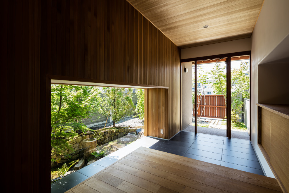 Diseño de hall de estilo zen con paredes marrones, suelo de baldosas de cerámica, puerta simple, suelo negro, madera y madera