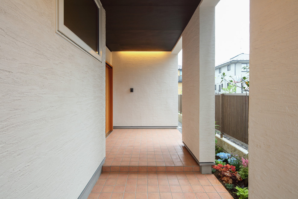 Mittelgroße Asiatische Haustür mit weißer Wandfarbe, Porzellan-Bodenfliesen, Schiebetür, hellbrauner Holzhaustür und orangem Boden in Sonstige
