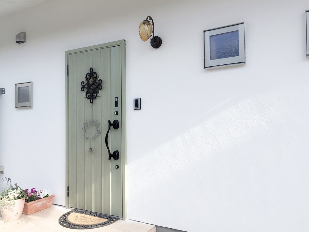 Aménagement d'une porte d'entrée méditerranéenne avec un mur blanc, parquet clair, une porte simple, une porte verte et un sol blanc.
