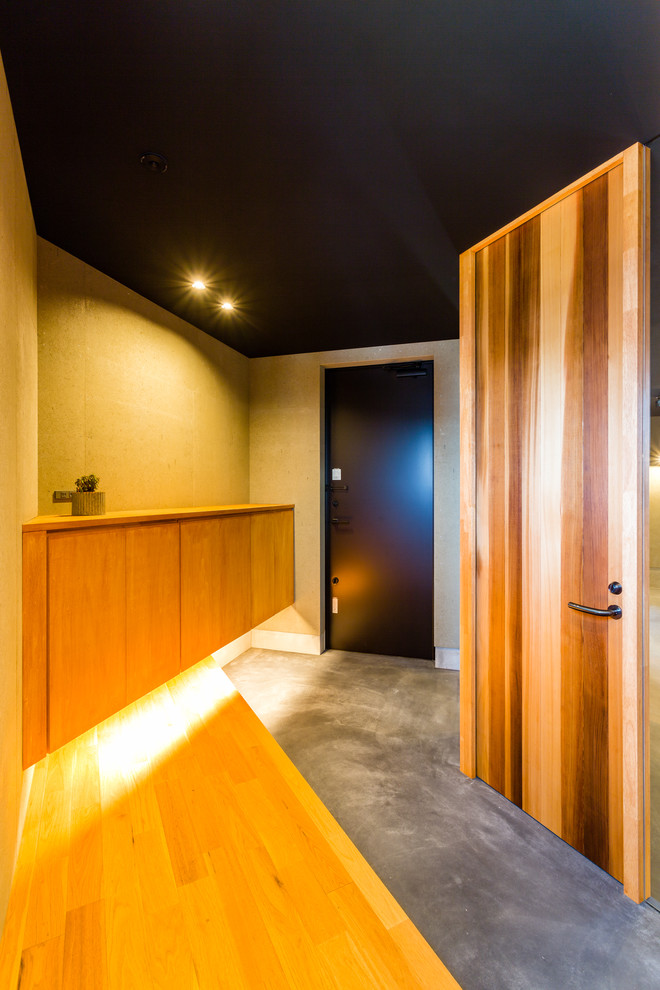 Ejemplo de hall asiático con paredes marrones, suelo de cemento, puerta simple, puerta negra y suelo gris