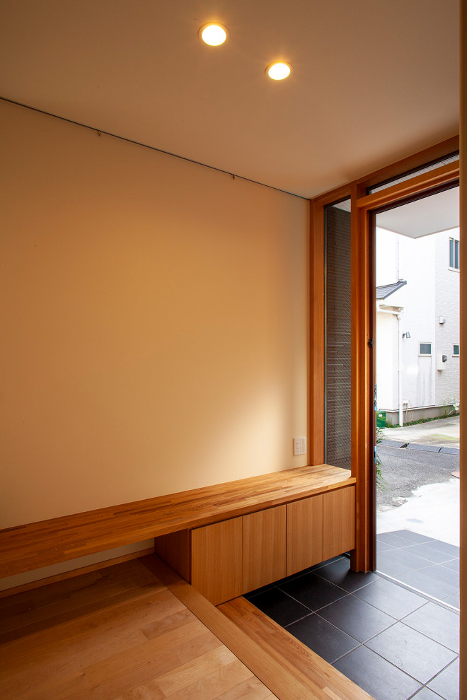 Idee per un corridoio minimalista di medie dimensioni con pareti bianche, pavimento in gres porcellanato, una porta singola, una porta in legno bruno e pavimento grigio
