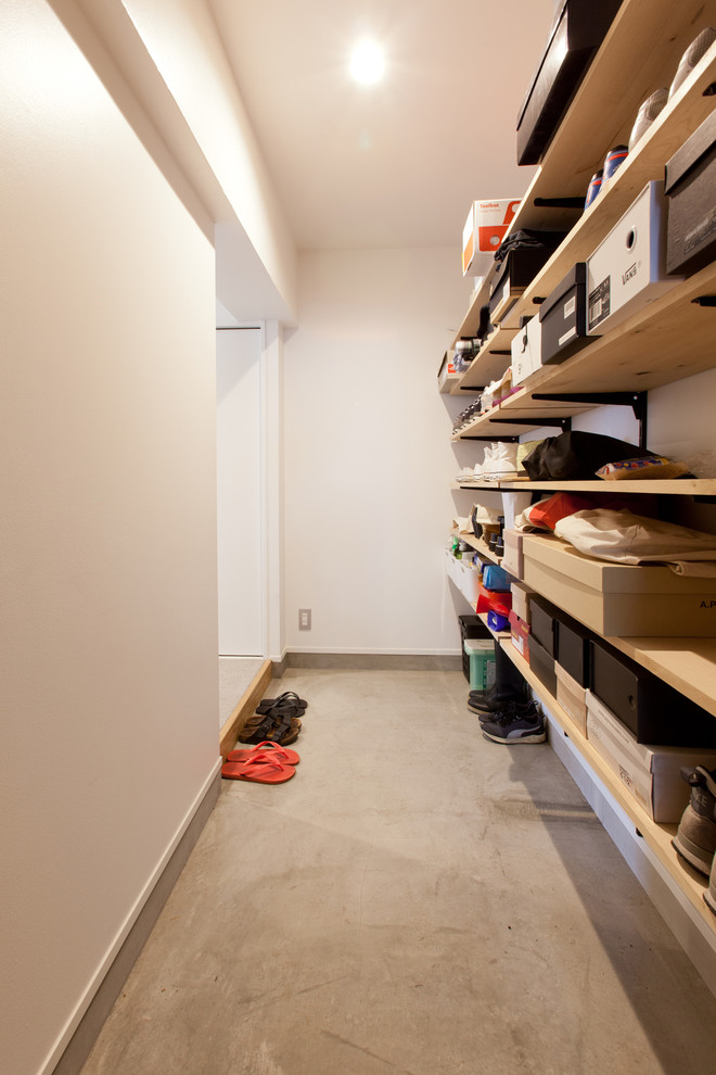 Photo of a contemporary boot room in Tokyo with white walls and concrete flooring.