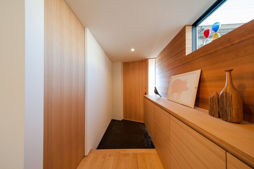Imagen de hall moderno de tamaño medio con paredes blancas, puerta simple, puerta de madera en tonos medios y suelo negro