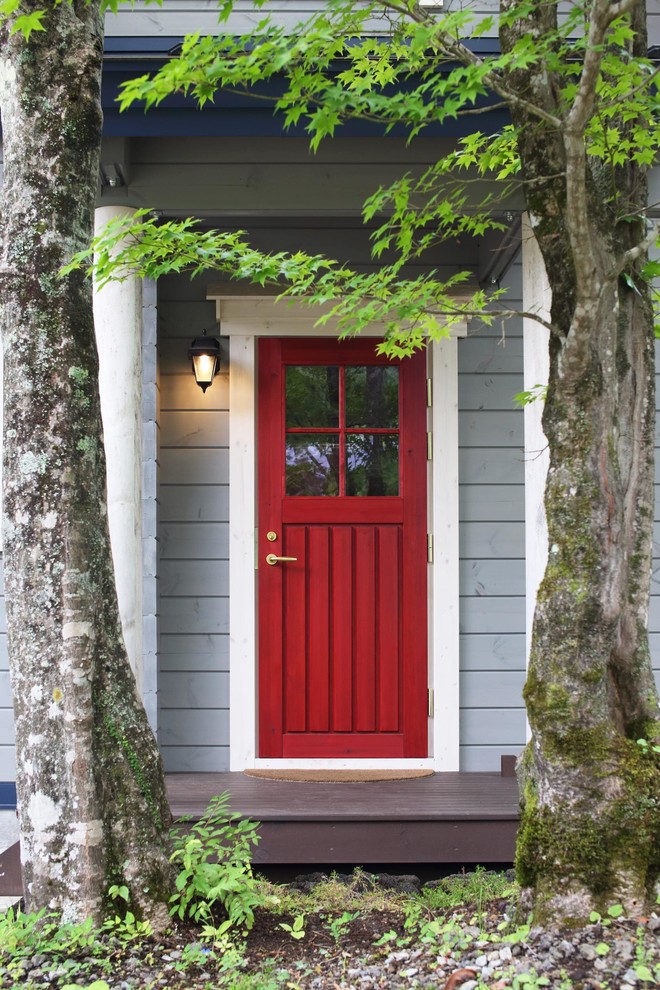カントリー風のおしゃれな玄関ドア (青い壁、塗装フローリング、赤いドア、茶色い床) の写真
