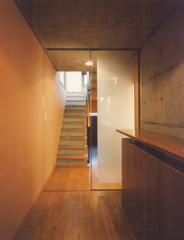 На фото: узкая прихожая среднего размера в стиле модернизм с белыми стенами, паркетным полом среднего тона, одностворчатой входной дверью, входной дверью из дерева среднего тона и коричневым полом