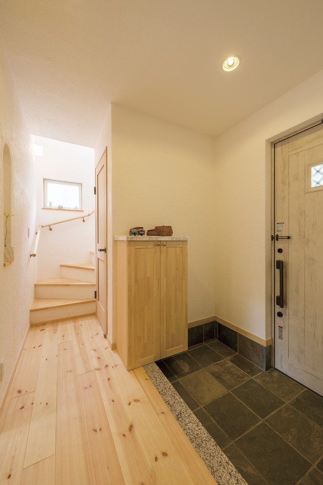 Inspiration för nordiska entréer, med vita väggar, ljust trägolv, en enkeldörr, en grå dörr och brunt golv