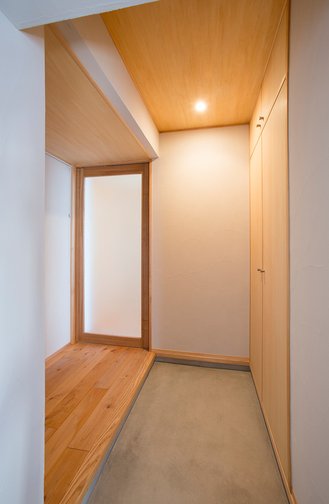Ispirazione per un corridoio moderno di medie dimensioni con pareti bianche, pavimento in legno massello medio, una porta in legno chiaro e pavimento beige