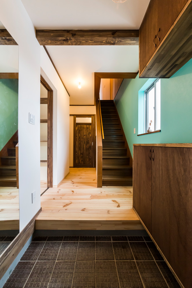 Esempio di un piccolo corridoio etnico con pareti blu, pavimento in legno massello medio, una porta in metallo e pavimento beige