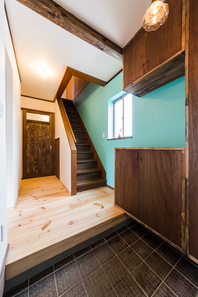 Foto di un piccolo corridoio con pareti blu, pavimento in legno massello medio, una porta scorrevole, una porta in metallo e pavimento beige