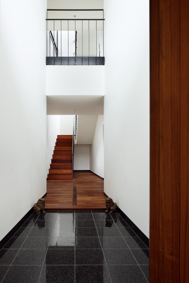 Inspiration pour une entrée minimaliste avec un couloir, un mur blanc, un sol en marbre, une porte simple, une porte en bois brun et un sol noir.