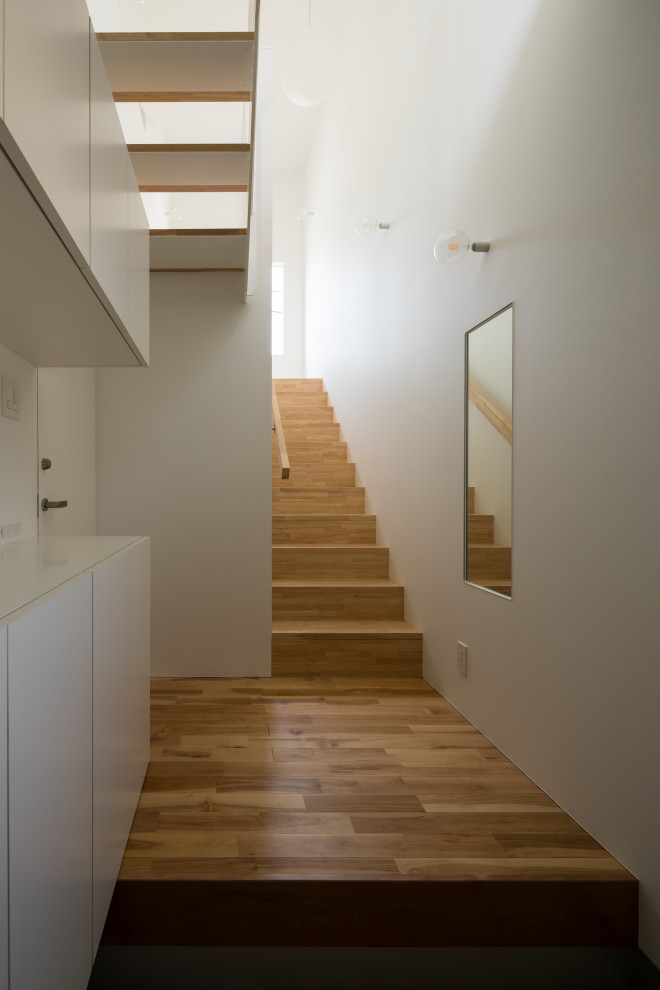 This is an example of a medium sized modern hallway in Other with white walls, medium hardwood flooring, a single front door, a wallpapered ceiling and wallpapered walls.