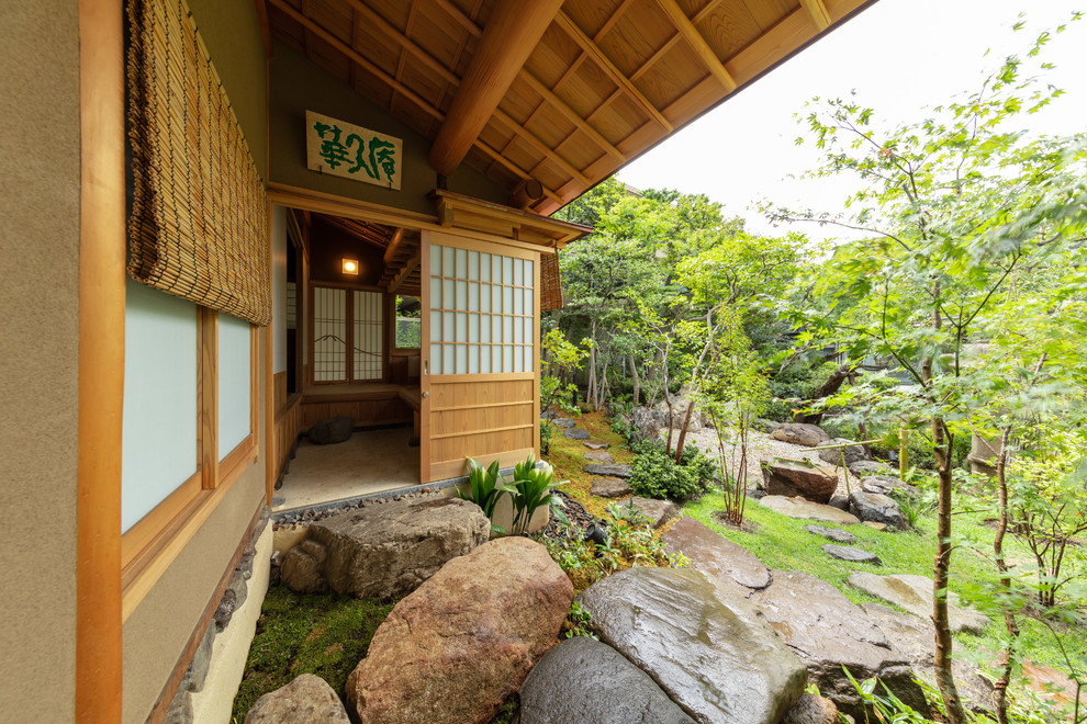 Asiatische Haustür mit grauer Wandfarbe, Schiebetür, hellbrauner Holzhaustür und grauem Boden in Tokio