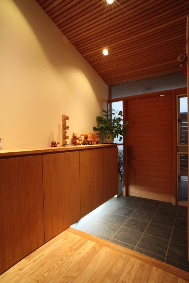 Réalisation d'une porte d'entrée minimaliste de taille moyenne avec un mur blanc, un sol en carrelage de porcelaine, une porte simple, une porte en bois brun, un sol gris et un plafond en bois.