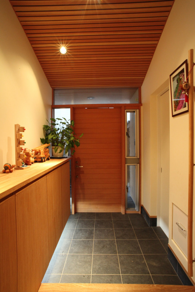 他の地域にあるお手頃価格の中くらいなアジアンスタイルのおしゃれな玄関ドア (白い壁、磁器タイルの床、木目調のドア、グレーの床、板張り天井) の写真