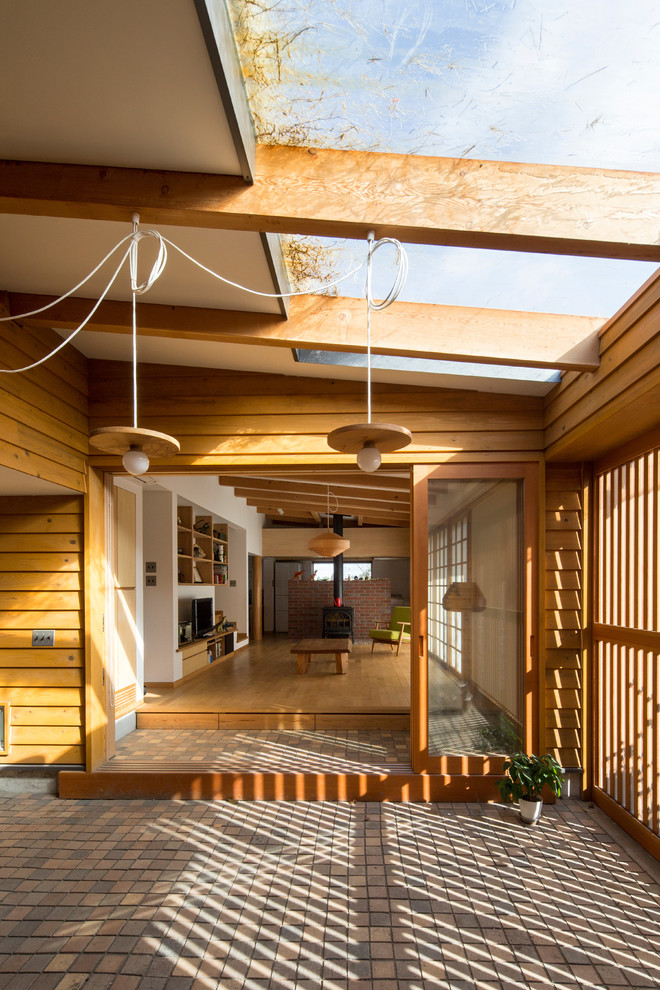 Idéer för en asiatisk entré, med bruna väggar, mellanmörk trädörr och grått golv
