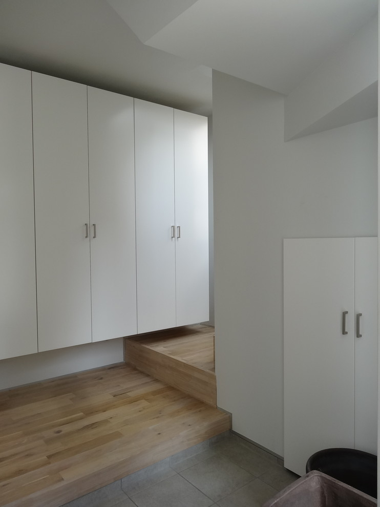 Idee per un corridoio minimalista di medie dimensioni con pareti bianche, pavimento con piastrelle in ceramica, una porta bianca, pavimento grigio e una porta singola