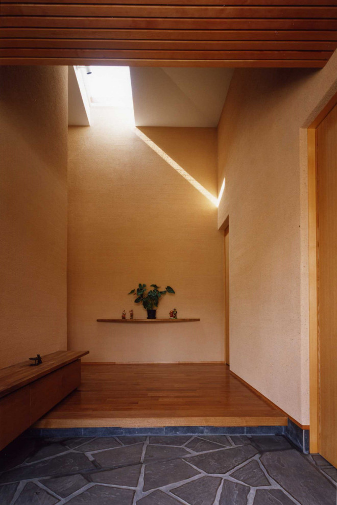 Modelo de hall minimalista de tamaño medio con paredes beige, suelo de madera en tonos medios, puerta simple, puerta de madera oscura, suelo marrón y machihembrado