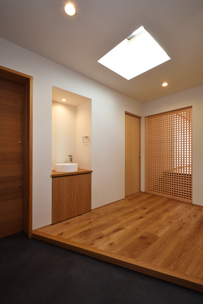 Ejemplo de puerta principal de estilo zen con paredes marrones, suelo de cemento, puerta de madera en tonos medios y suelo gris