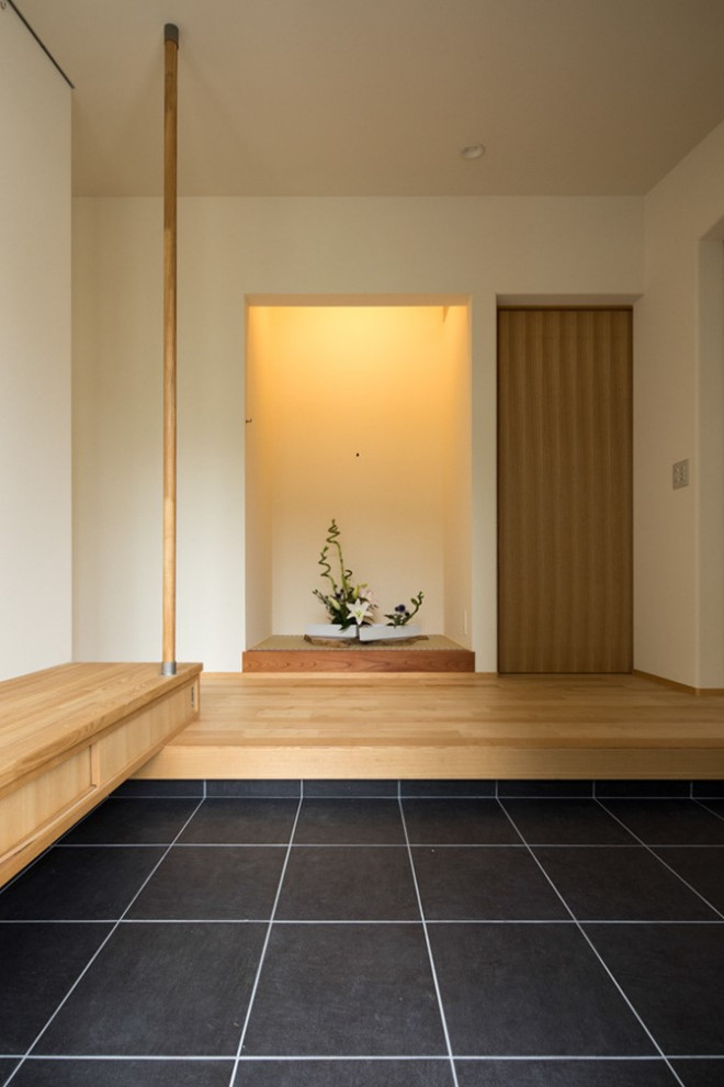 Источник вдохновения для домашнего уюта: узкая прихожая среднего размера в восточном стиле с белыми стенами, полом из керамогранита, черной входной дверью и серым полом
