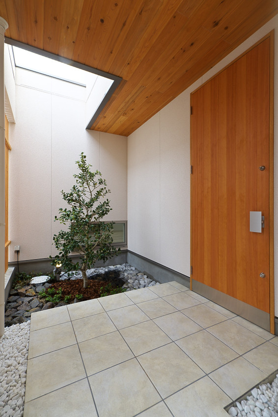 Inspiration pour une porte d'entrée nordique de taille moyenne avec un mur blanc, une porte simple, une porte en bois brun, un sol en carrelage de céramique, un sol beige et un plafond en bois.