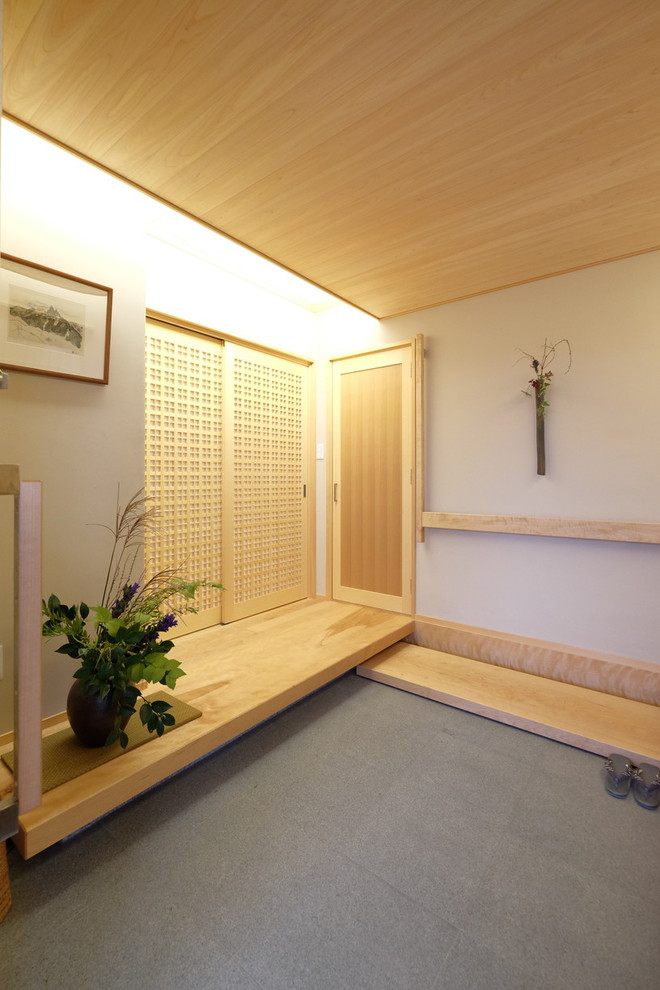 Cette photo montre une petite entrée asiatique avec sol en granite, une porte coulissante, une porte en bois clair, un couloir, un mur beige et un sol gris.