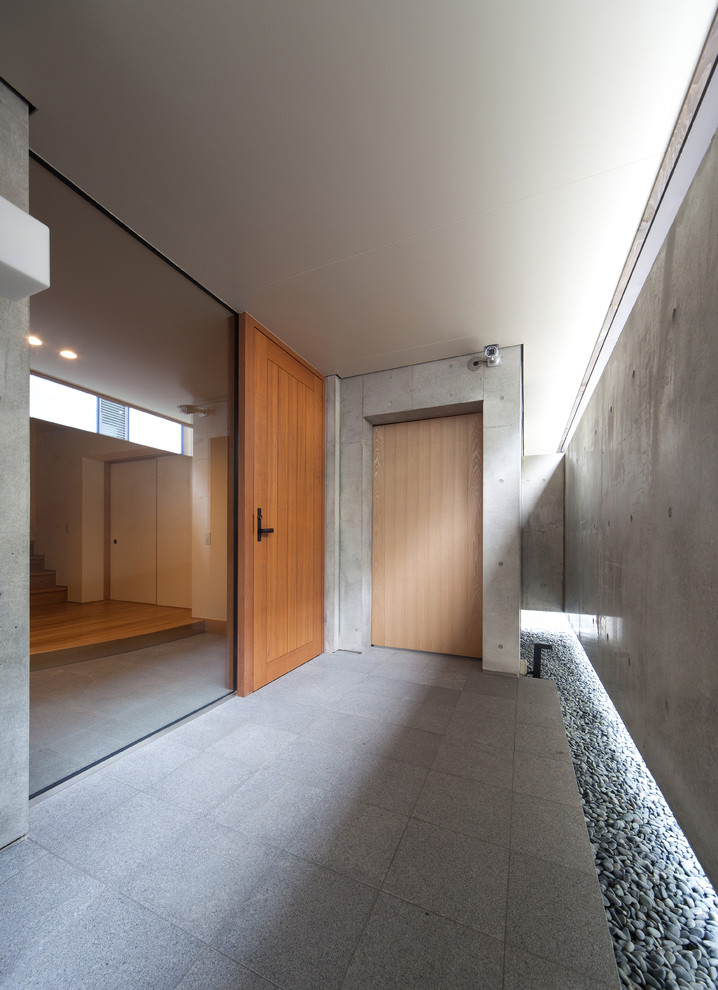 Idée de décoration pour une entrée asiatique avec une porte simple, une porte en bois brun et un sol gris.