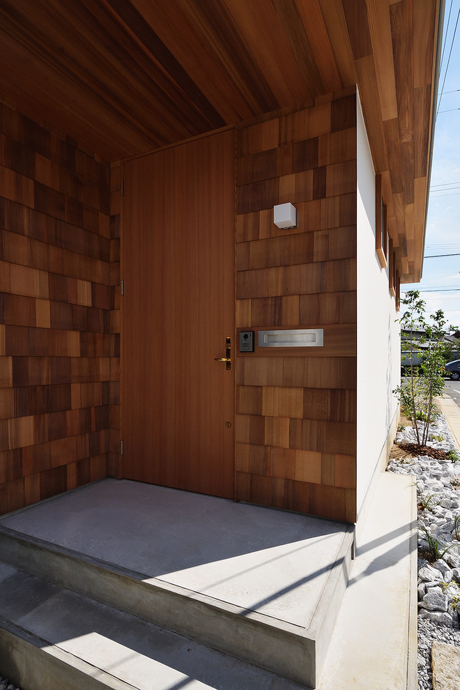 Foto di una piccola porta d'ingresso nordica con una porta in legno chiaro, una porta singola, pareti marroni, pavimento in cemento, pavimento grigio e soffitto in legno