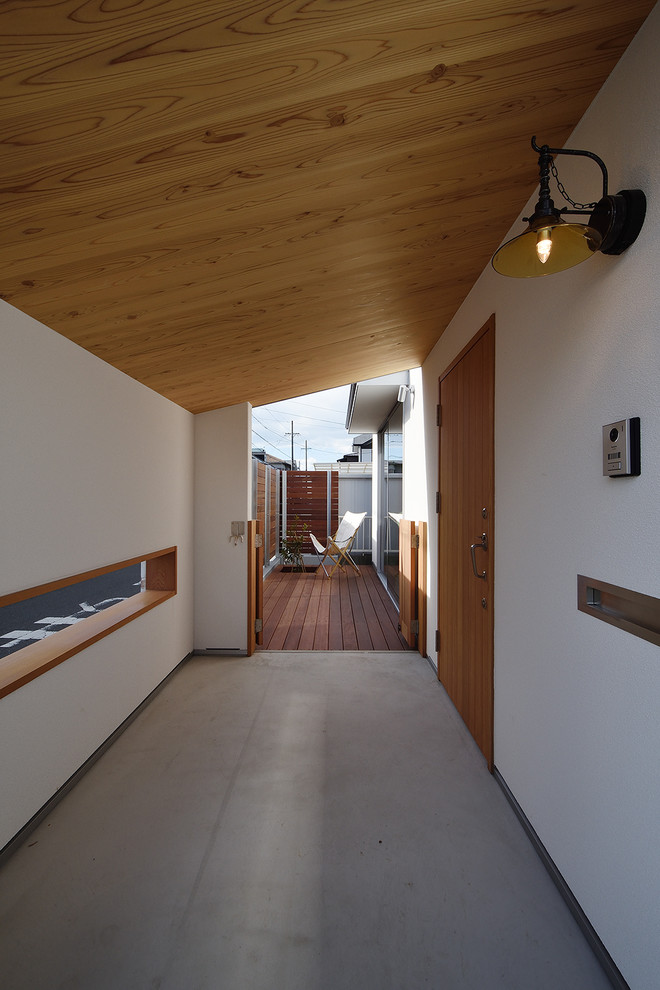 Aménagement d'une porte d'entrée scandinave de taille moyenne avec un mur blanc, sol en béton ciré, une porte simple, une porte en bois brun, un sol gris et un plafond en bois.