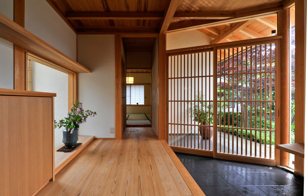 Exemple d'une entrée asiatique avec un mur blanc, une porte coulissante, un sol en bois brun et un sol marron.