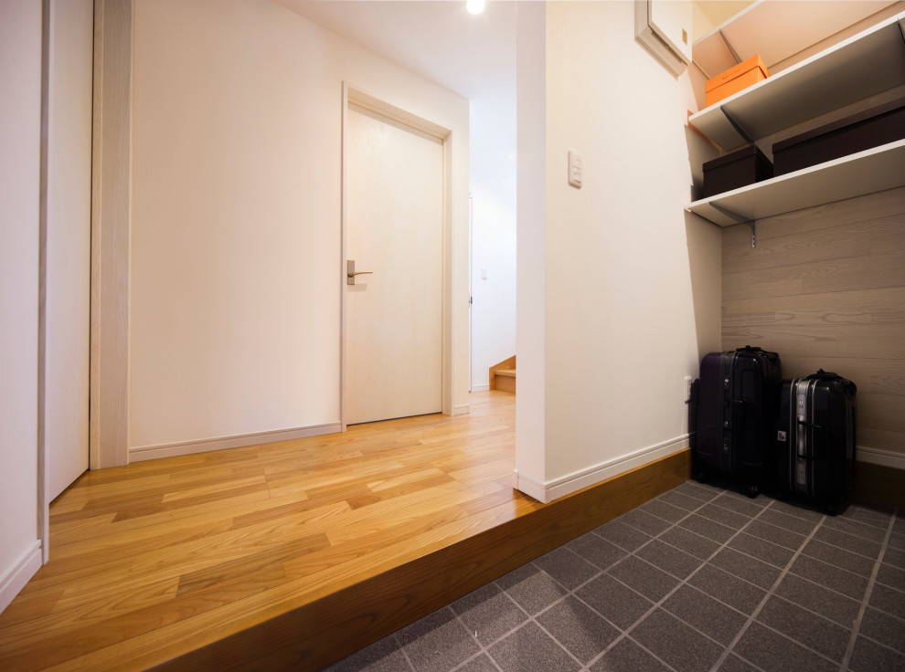 This is an example of a small modern boot room in Tokyo with white walls, ceramic flooring, a single front door, a white front door, grey floors, a wallpapered ceiling and wallpapered walls.