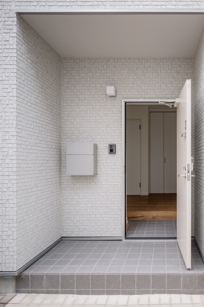 Foto di un piccolo ingresso moderno con pareti bianche, pavimento in gres porcellanato, una porta singola, una porta bianca, pavimento grigio, soffitto in carta da parati e carta da parati