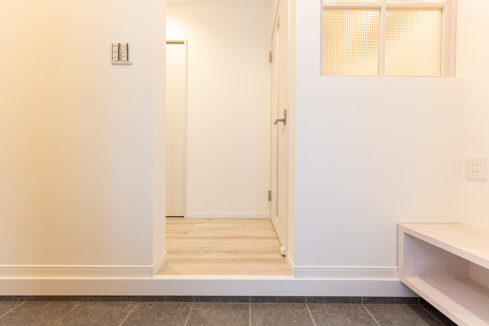 Ispirazione per un corridoio minimal di medie dimensioni con pareti bianche, pavimento con piastrelle in ceramica, una porta singola e una porta in legno chiaro