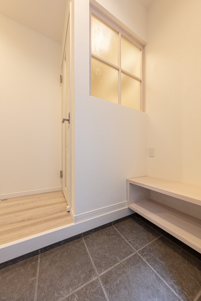 Ispirazione per un corridoio design di medie dimensioni con pareti bianche, pavimento con piastrelle in ceramica, una porta singola e una porta in legno chiaro