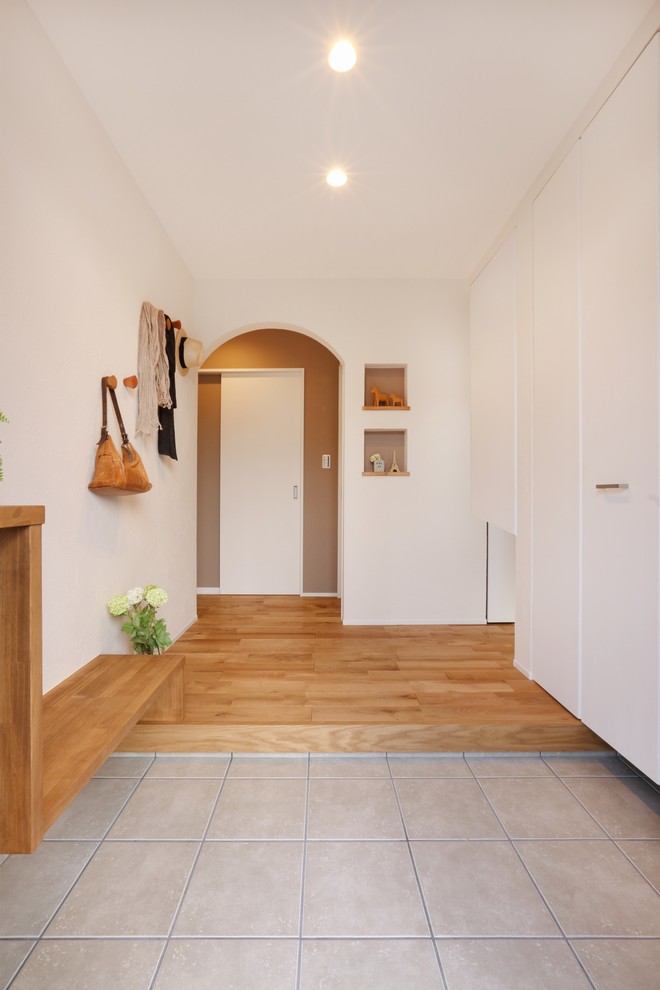 Photo of a scandinavian hallway in Other with beige walls, medium hardwood flooring, a single front door and a medium wood front door.