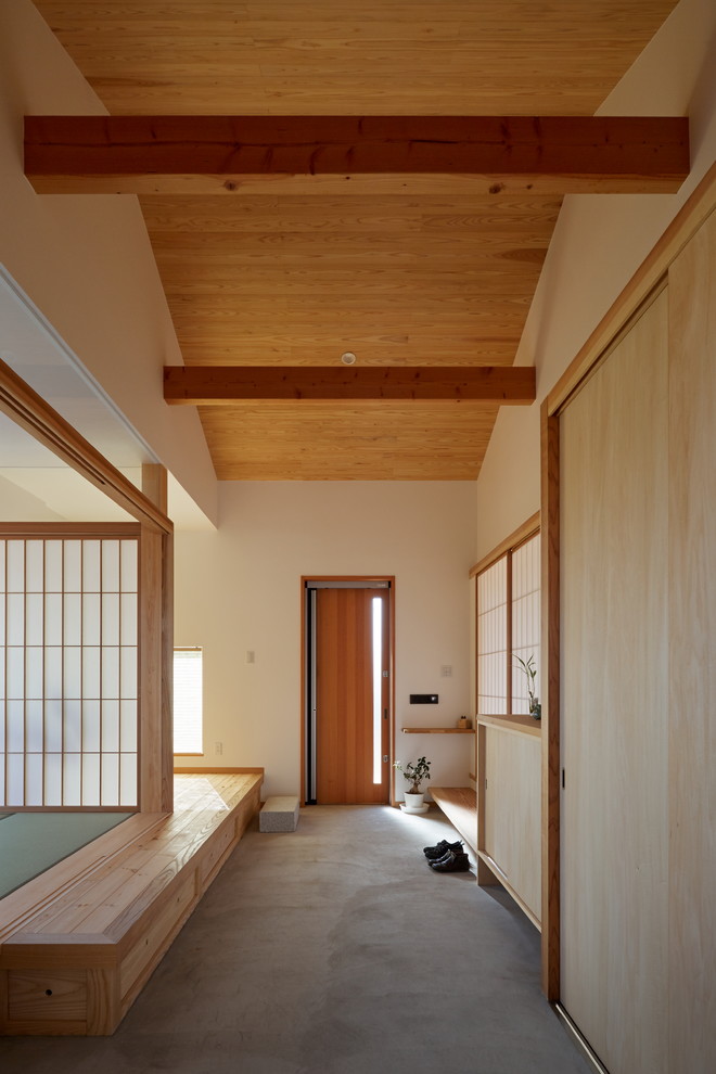 Asiatischer Eingang mit weißer Wandfarbe, Einzeltür, hellbrauner Holzhaustür und grauem Boden in Sonstige