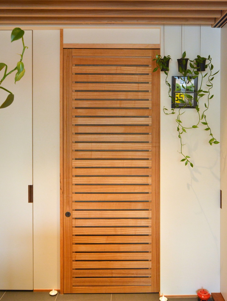 東京23区にある小さなコンテンポラリースタイルのおしゃれな玄関ロビー (白い壁、磁器タイルの床、淡色木目調のドア、グレーの床) の写真