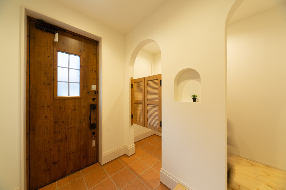 Diseño de hall campestre con paredes blancas, suelo de baldosas de terracota, puerta simple, puerta de madera oscura, suelo naranja, papel pintado y papel pintado