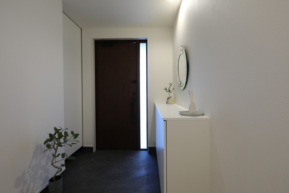 Idées déco pour une entrée moderne de taille moyenne avec un couloir, un mur blanc, sol en béton ciré et un sol noir.