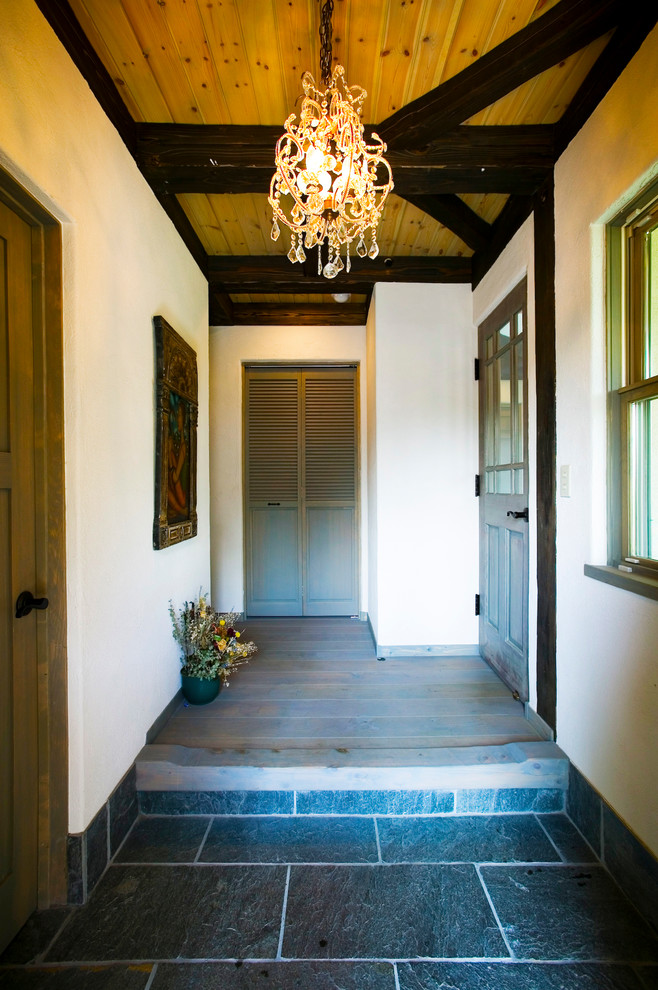 Réalisation d'une entrée chalet avec un couloir, sol en granite, un sol bleu et un mur noir.