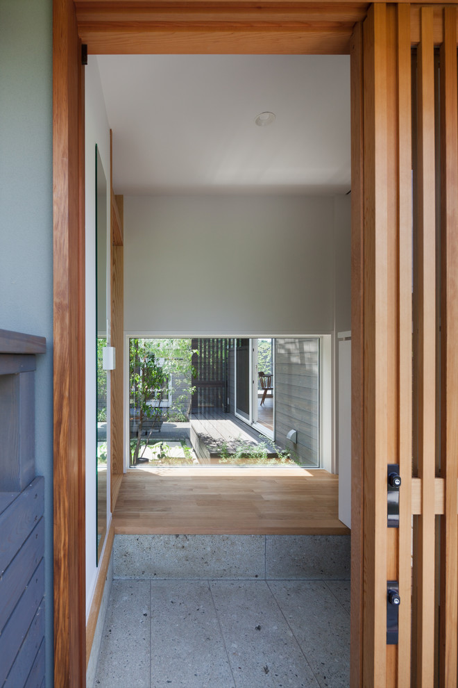 На фото: узкая прихожая с белыми стенами, раздвижной входной дверью, входной дверью из дерева среднего тона и серым полом с