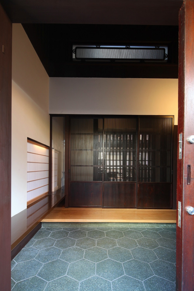 Imagen de hall asiático grande con paredes blancas, suelo de madera clara, puerta corredera, puerta de madera oscura y vigas vistas