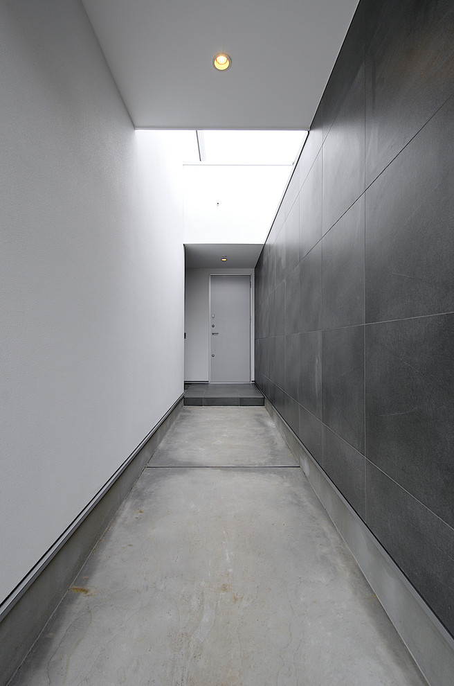 Idee per un ingresso moderno con pareti nere, pavimento in cemento, una porta singola, una porta in metallo e pavimento grigio