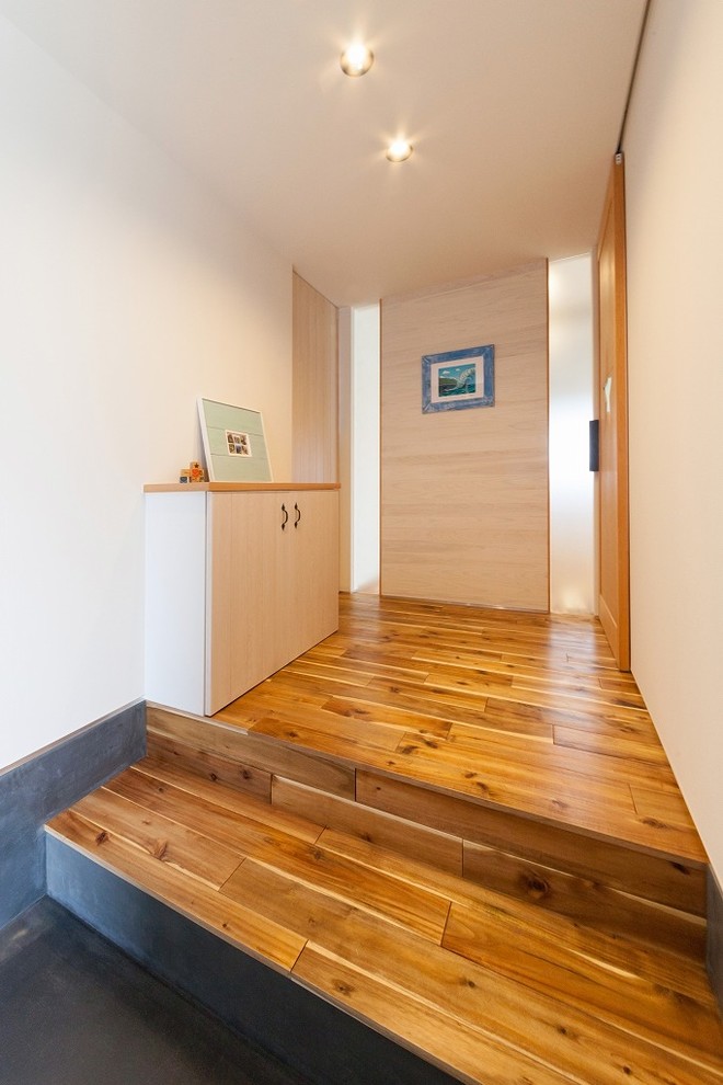 Idées déco pour une entrée contemporaine de taille moyenne avec un couloir, un mur blanc, un sol en bois brun et un sol marron.